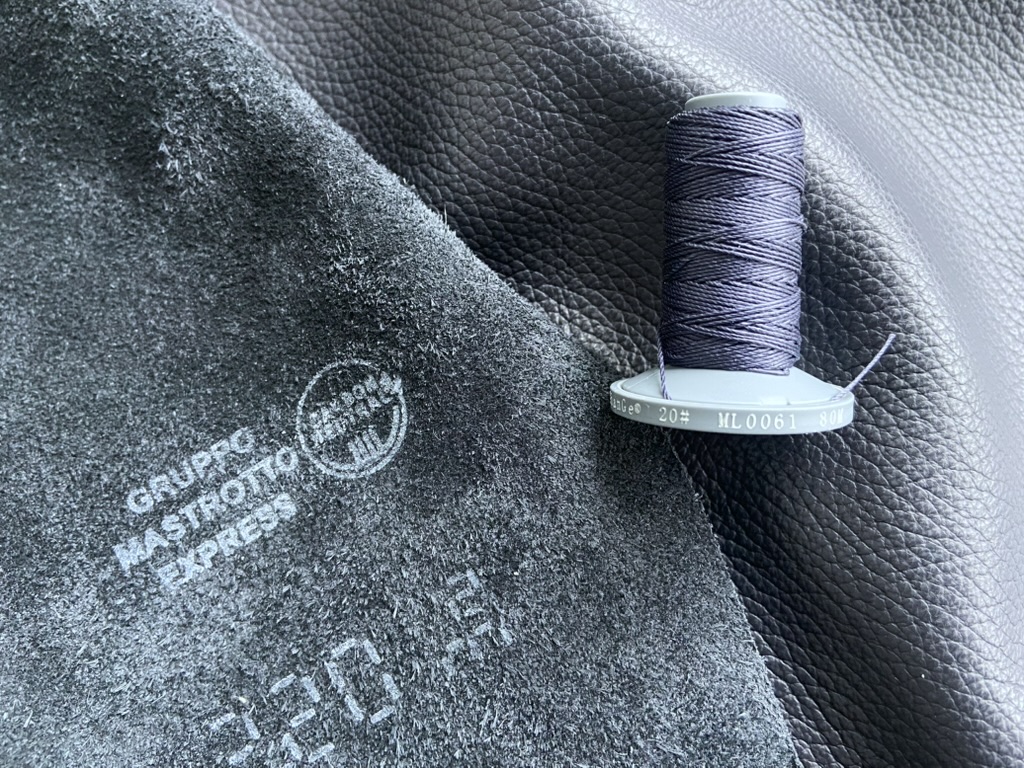 Зображення темно-синьої шкіри Gruppo Mastrotto Express та відповідної за кольором нитки XianGe Twist для роботи зі шкірою.