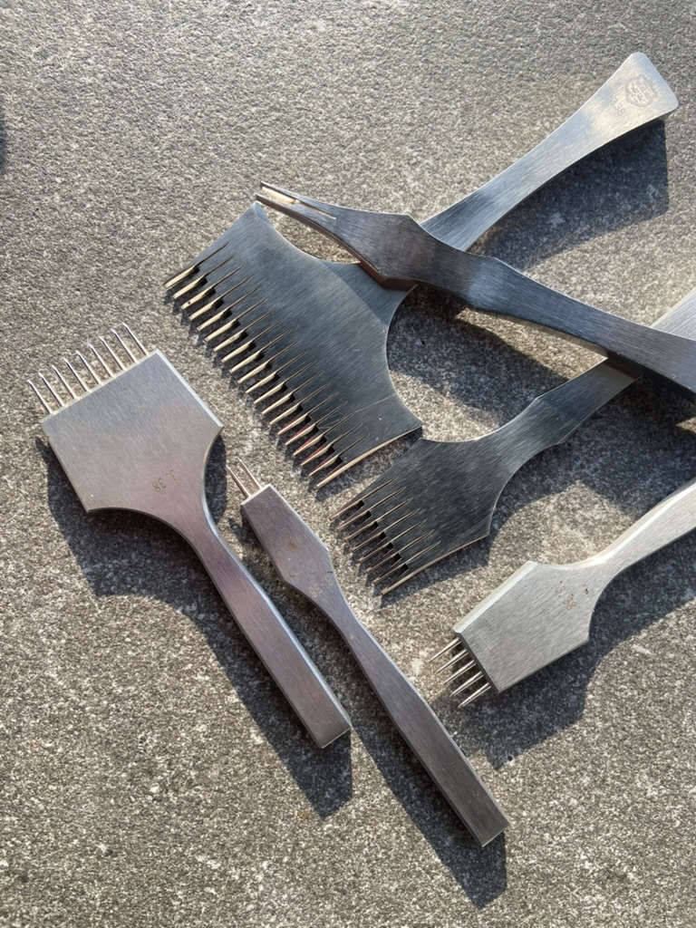 Крупний план професійних пробійників для шкіри зі сталі, розташованих на сірій поверхні.